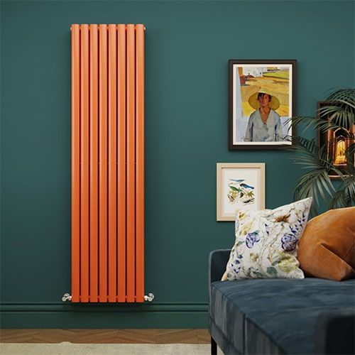 A tall orange aruba vertical designer radiator on a green wall in a sitting room