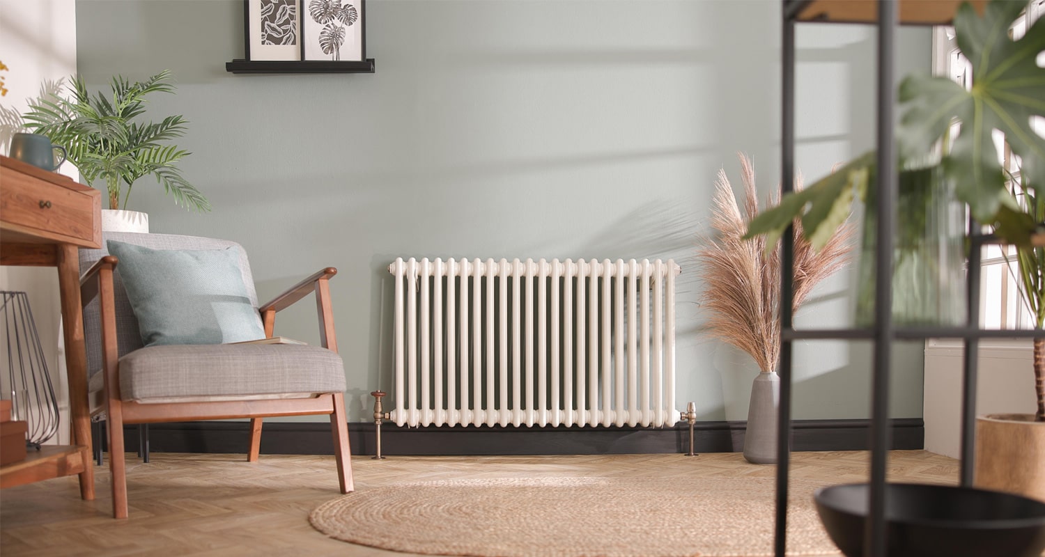 White Windsor Traditional Column Radiator against a green wall in a sitting room space